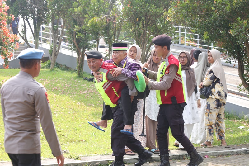 Petugas dari Polres Kuningan menggendong jmaah haji lansia saat pelepasan jemaah haji Kloter 13 di Kuningan Islamic Center (KIC), Kamis (23/5/2024). FOTO: Diskominfo Kuningan